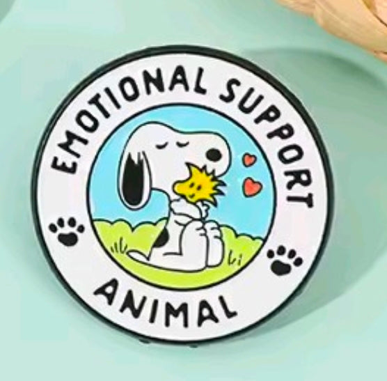 Close-up round enamel pin reading Emotional Support Animal around Snoopy and bird