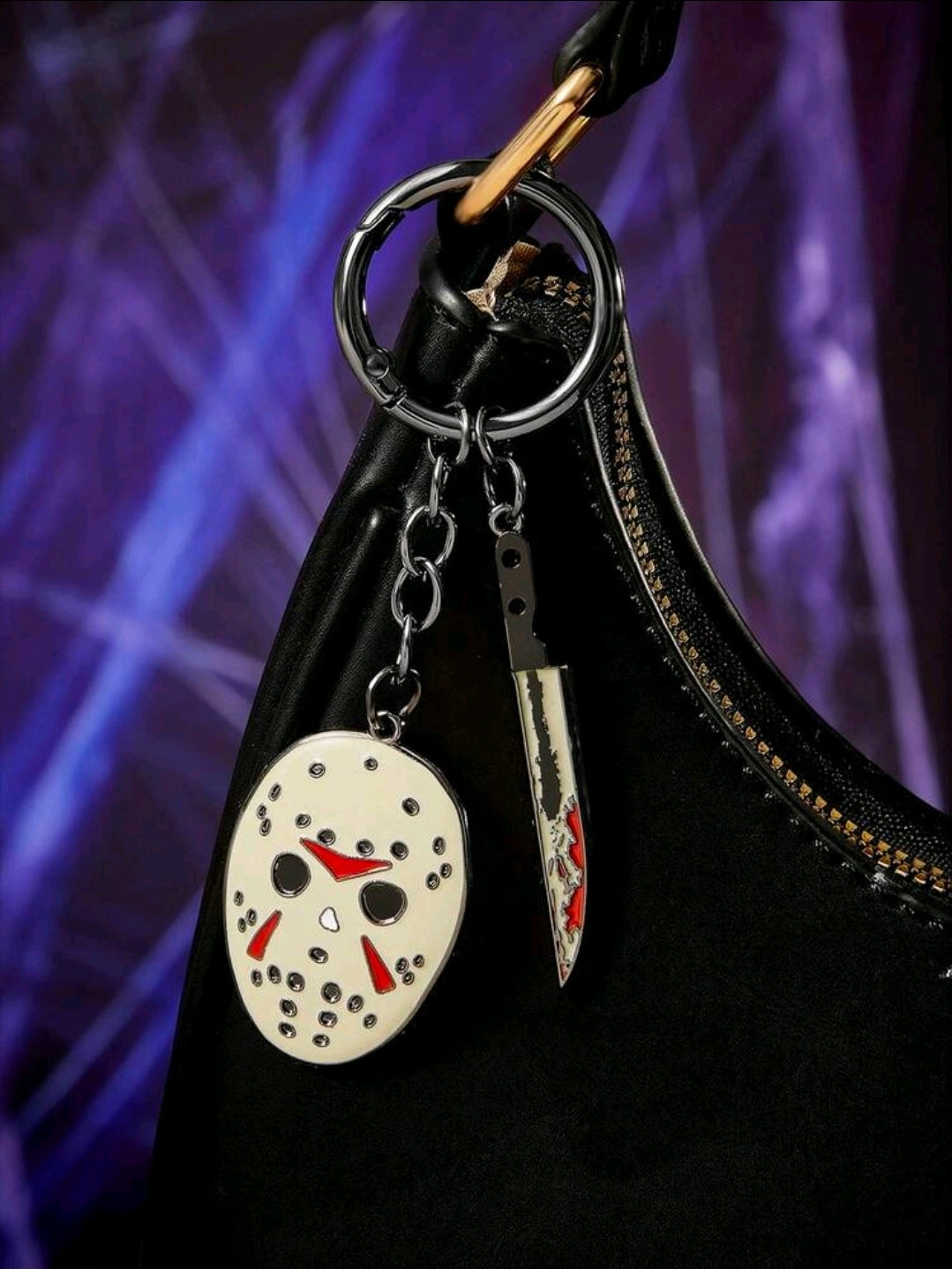 Enamel keychain with round mask charm and red-and-black dagger charm hanging from chain