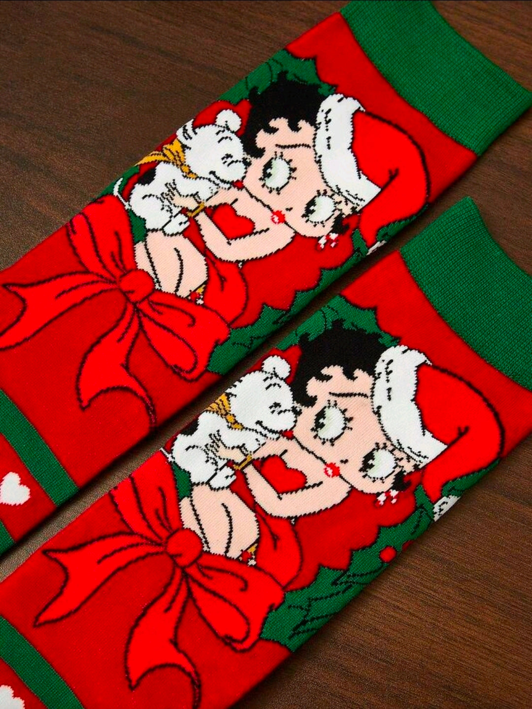 Pair of holiday crew socks close-up, red and green with Santa and Betty Boop-style faces