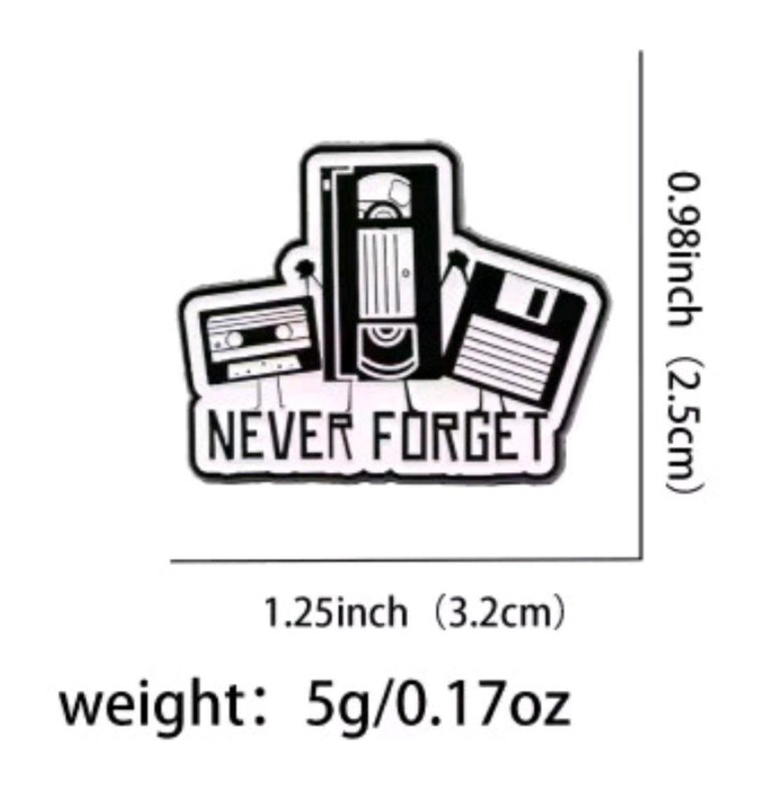 Enamel pin with camcorder and text 'Never Forget' on white card
