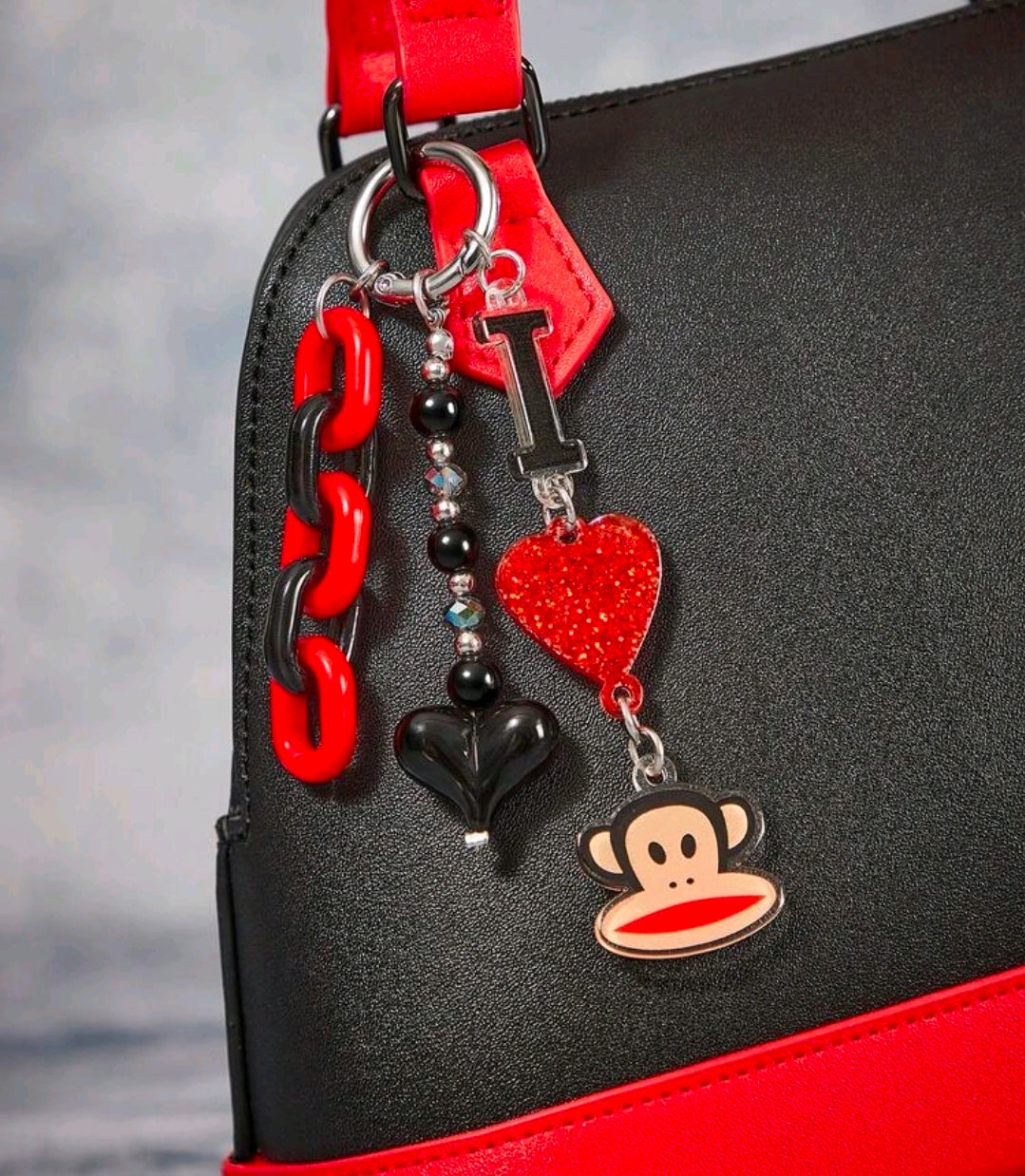 Red and black chain keychain charms hanging on a bag zipper pull