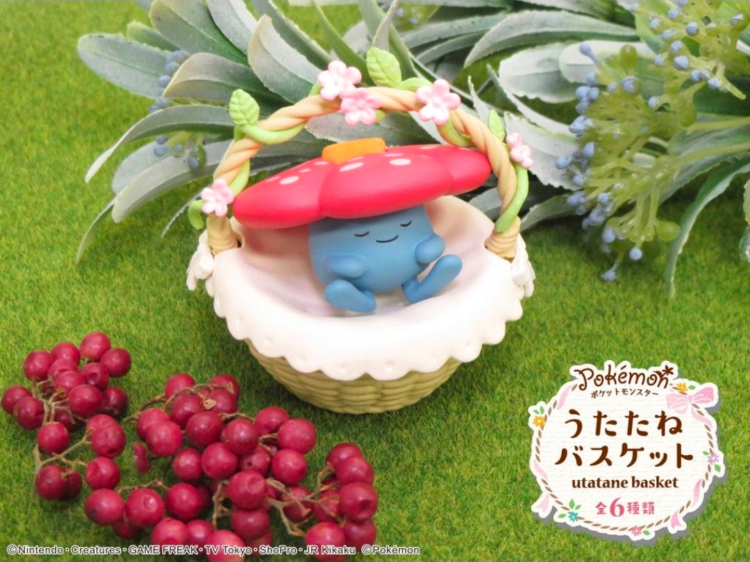 Miniature blue sleeping character in a red mushroom basket with greenery and pink flowers