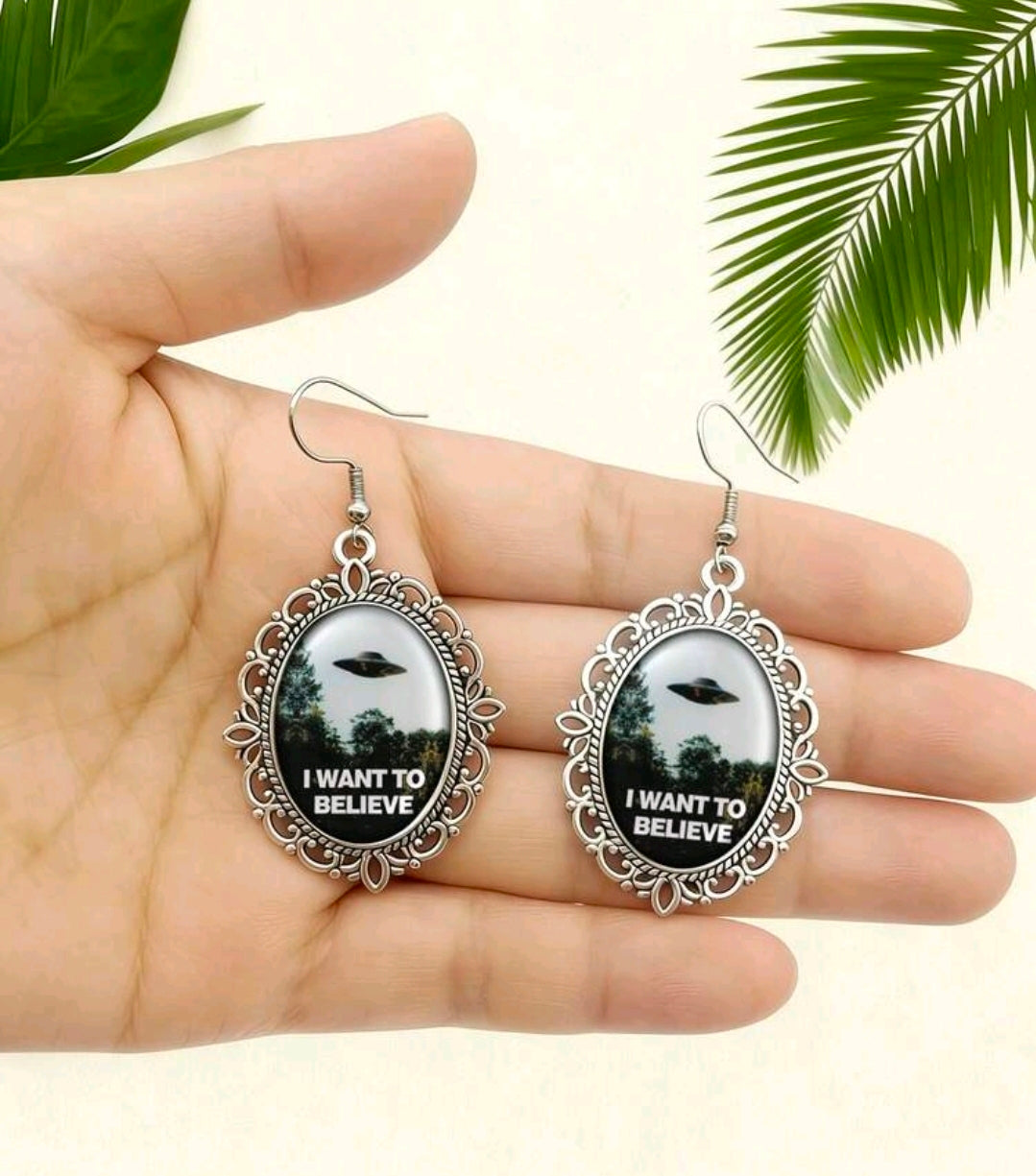 Silver oval dangle earrings with ornate frames and UFO graphic reading I Want to Believe