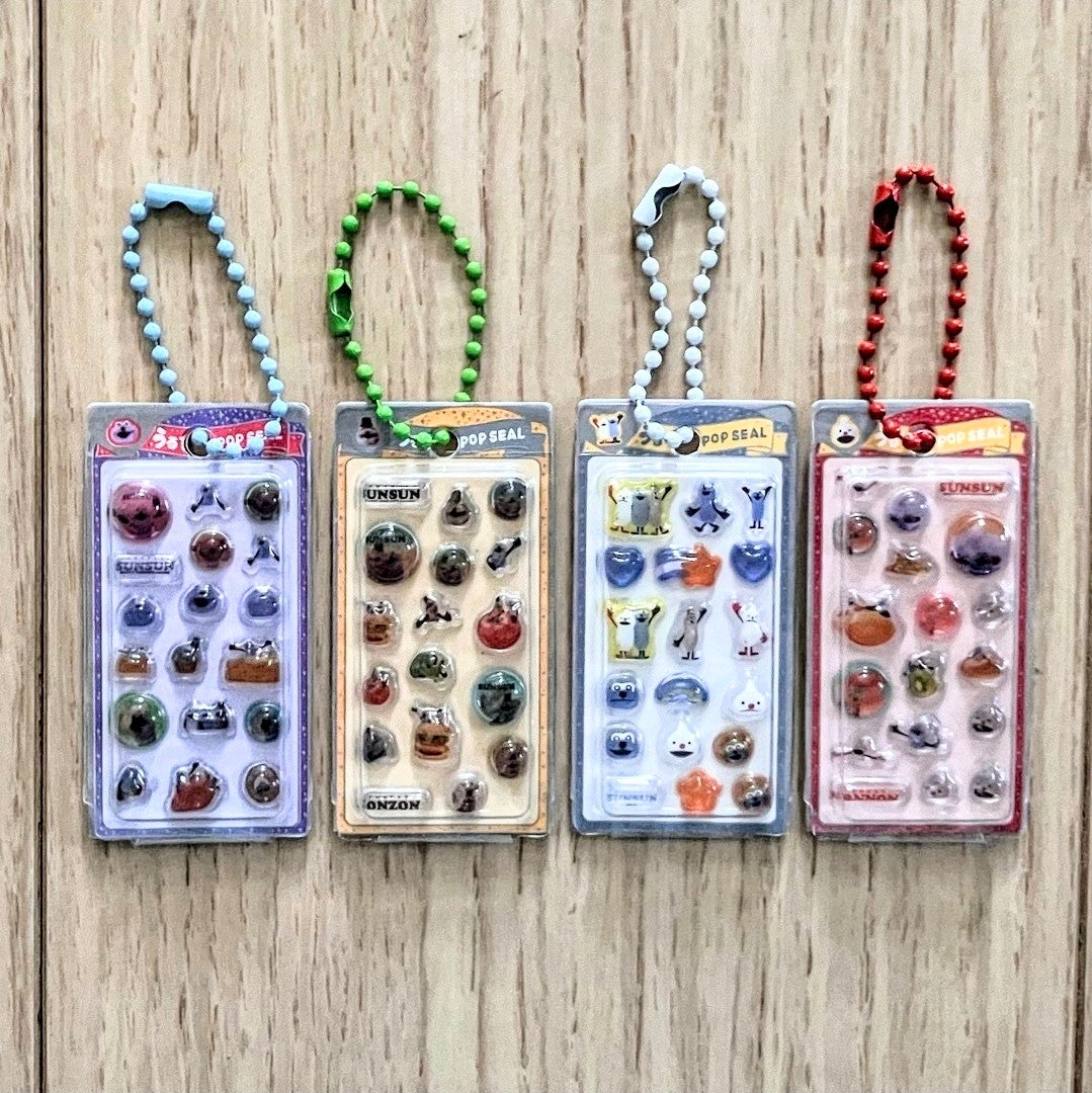 Sticker keychain gashapon blister packs with colorful bead loops, assorted character stickers