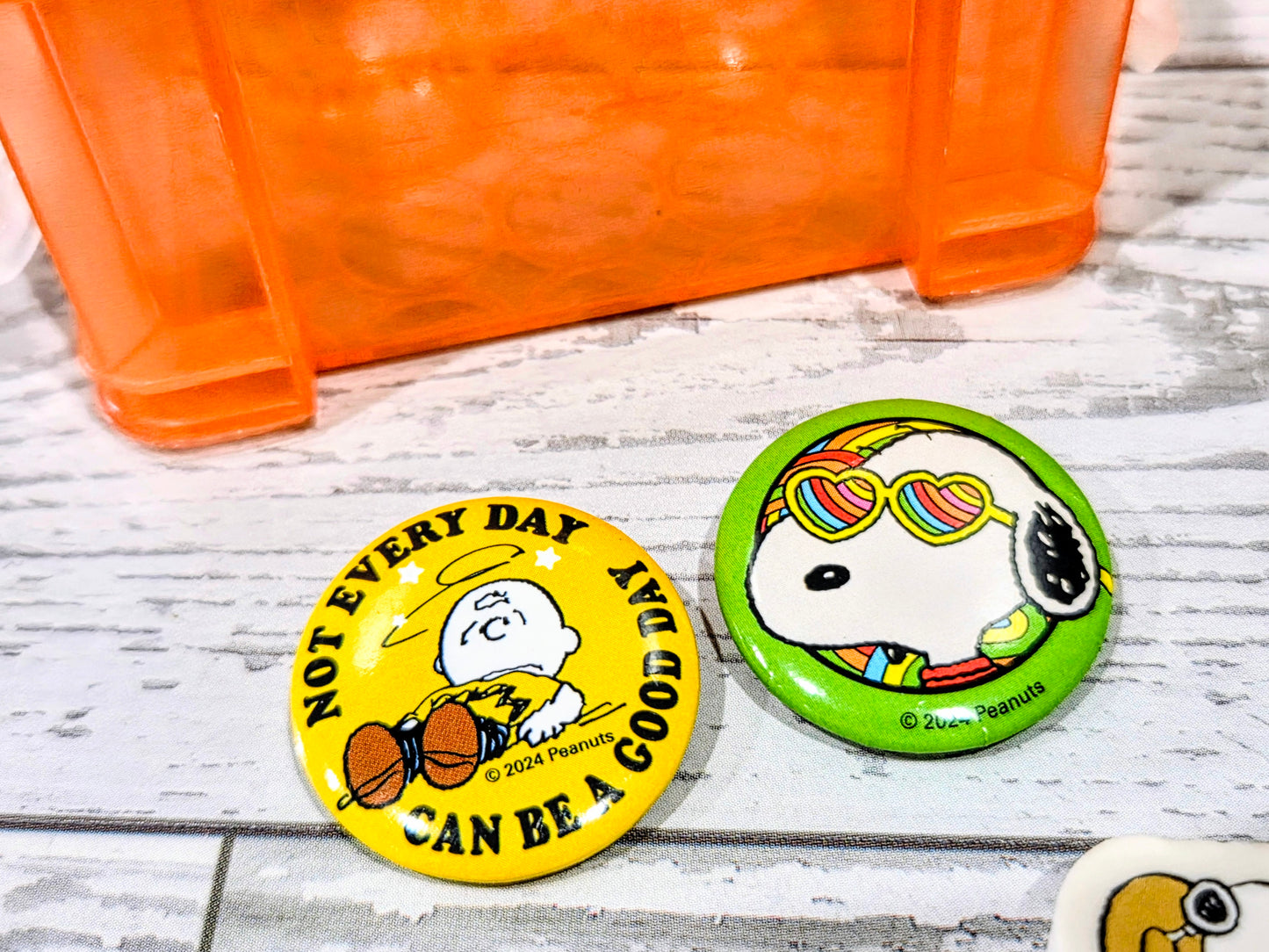 Snoopy-themed circular eraser stickers on table beside orange organizer box