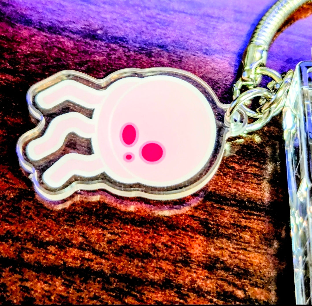 Hand-shaped charm keychain with pink face, attached to clear acrylic keyboard fidget