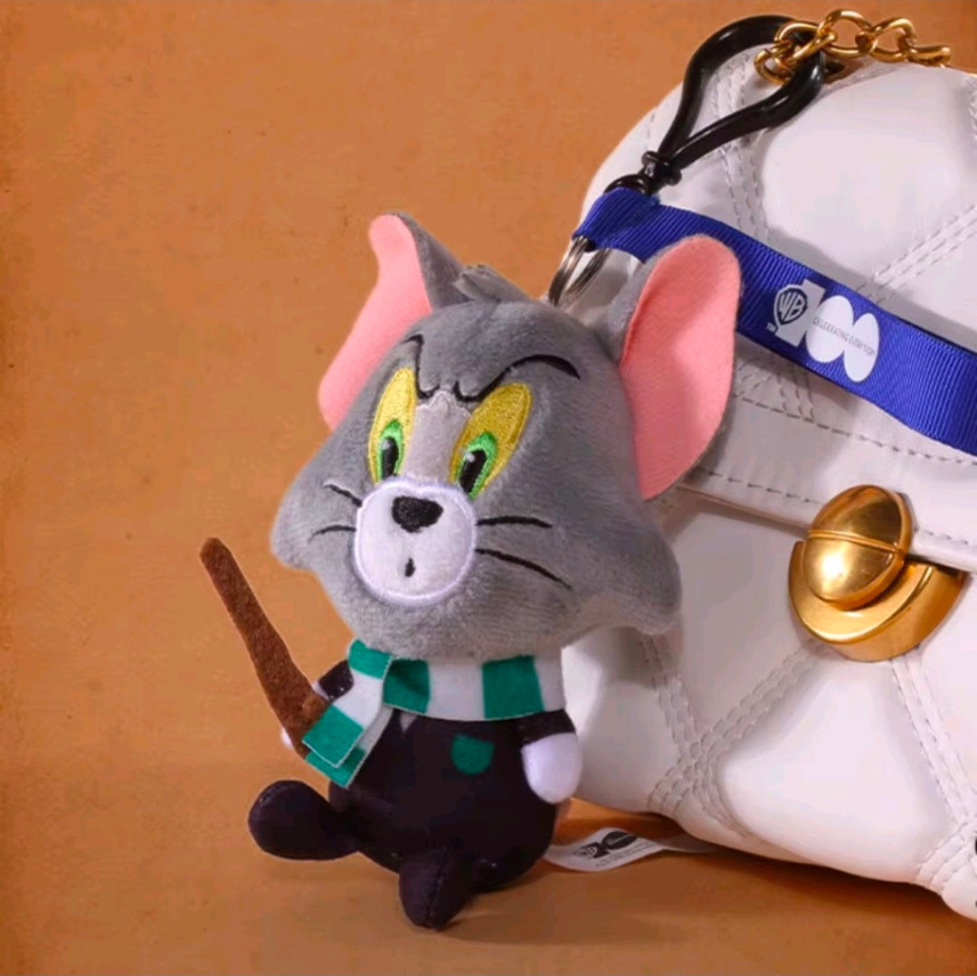 Grey wizard cat plush keychain close-up with blue strap, green eyes, and gold bell charm