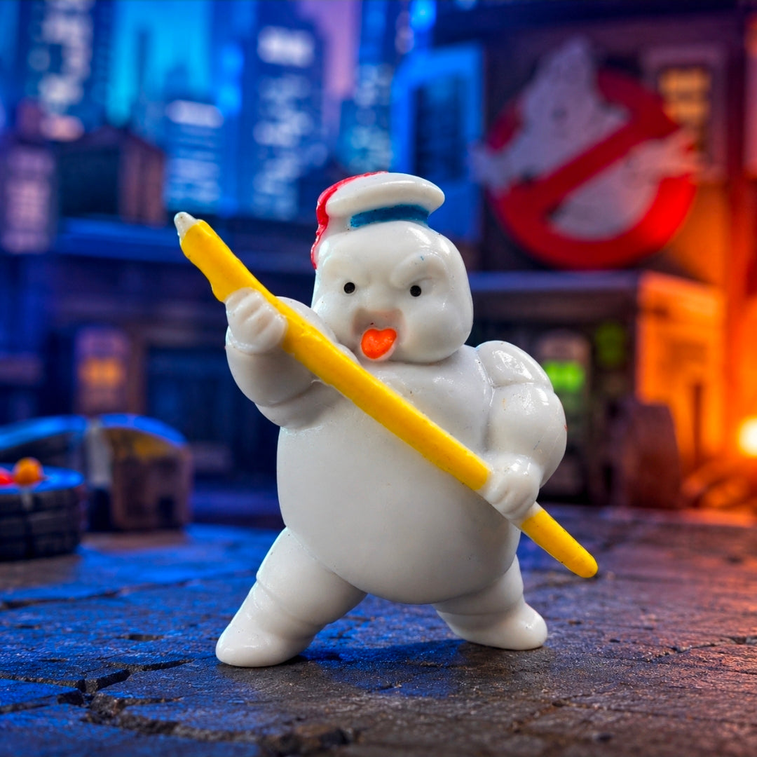 White mini figure holding yellow wand, orange nose, blue bib, posed