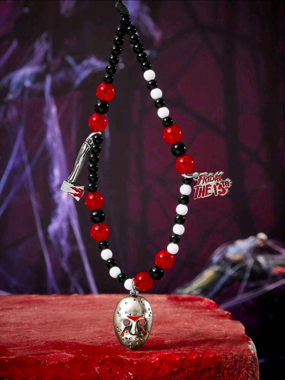 Beaded phone charm lanyard with black, red, and white beads and metal Jason mask charm