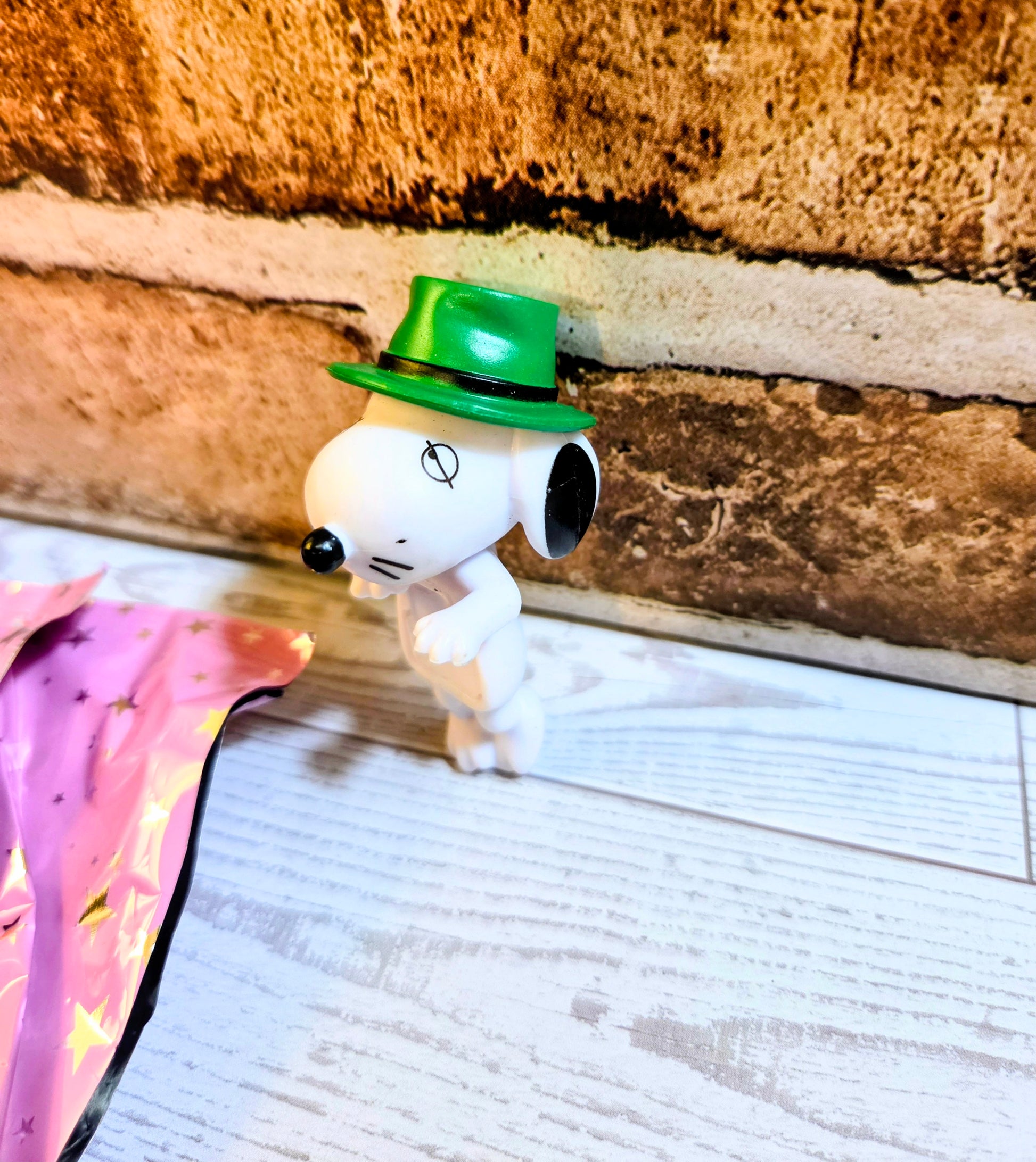 White mini figure with green top hat and whiskers, next to pink star fabric