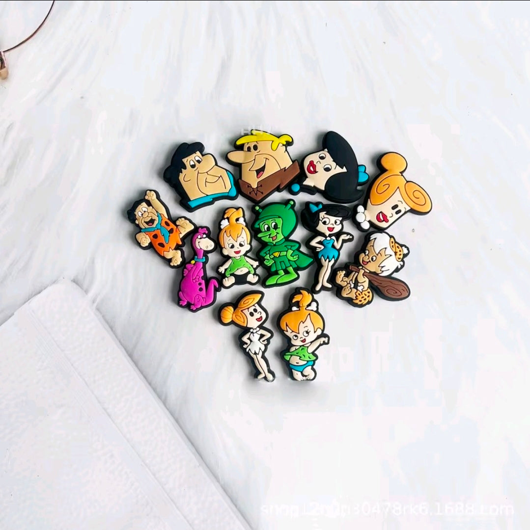 Assorted cartoon shoe and bag charms scattered on white fabric