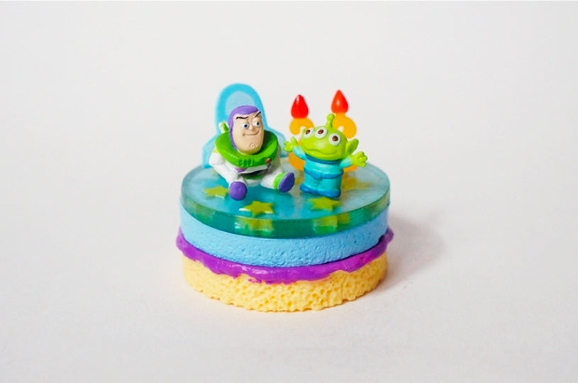 Colorful space-themed mini cake figure with Buzz and green alien on top