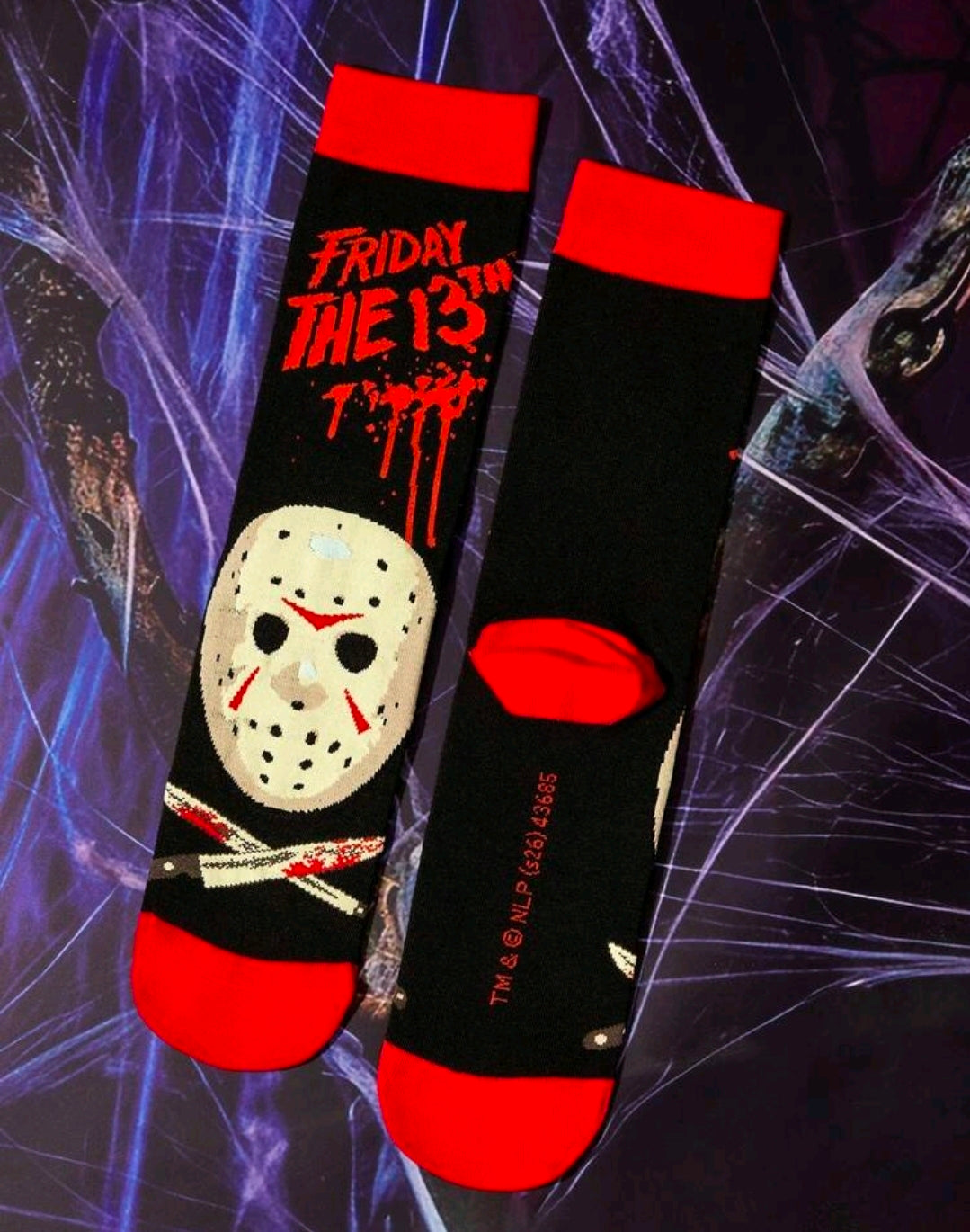 Two black crew socks with red cuffs, white hockey-mask faces, and red logo