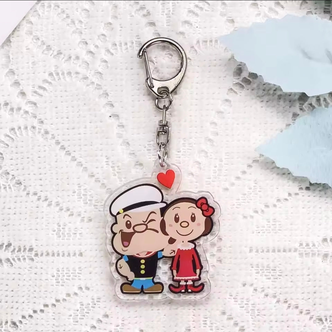 Acrylic keychain charm featuring Popeye and Olive Oyl standing together with a red heart