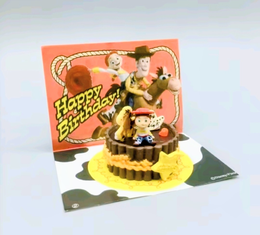 Packaged Western birthday cake mini figure on card with 'Happy Birthday' artwork
