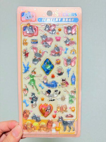 Sticker sheet held in hand with assorted animal and heart jewelry drop stickers