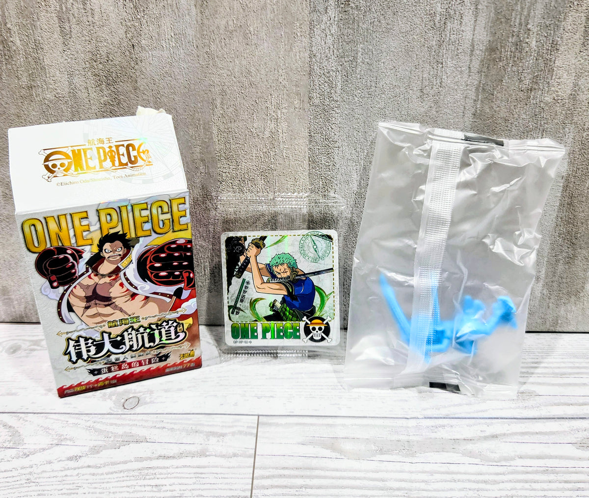 One Piece figure set with boxed character, small card, and blue figure in pouch
