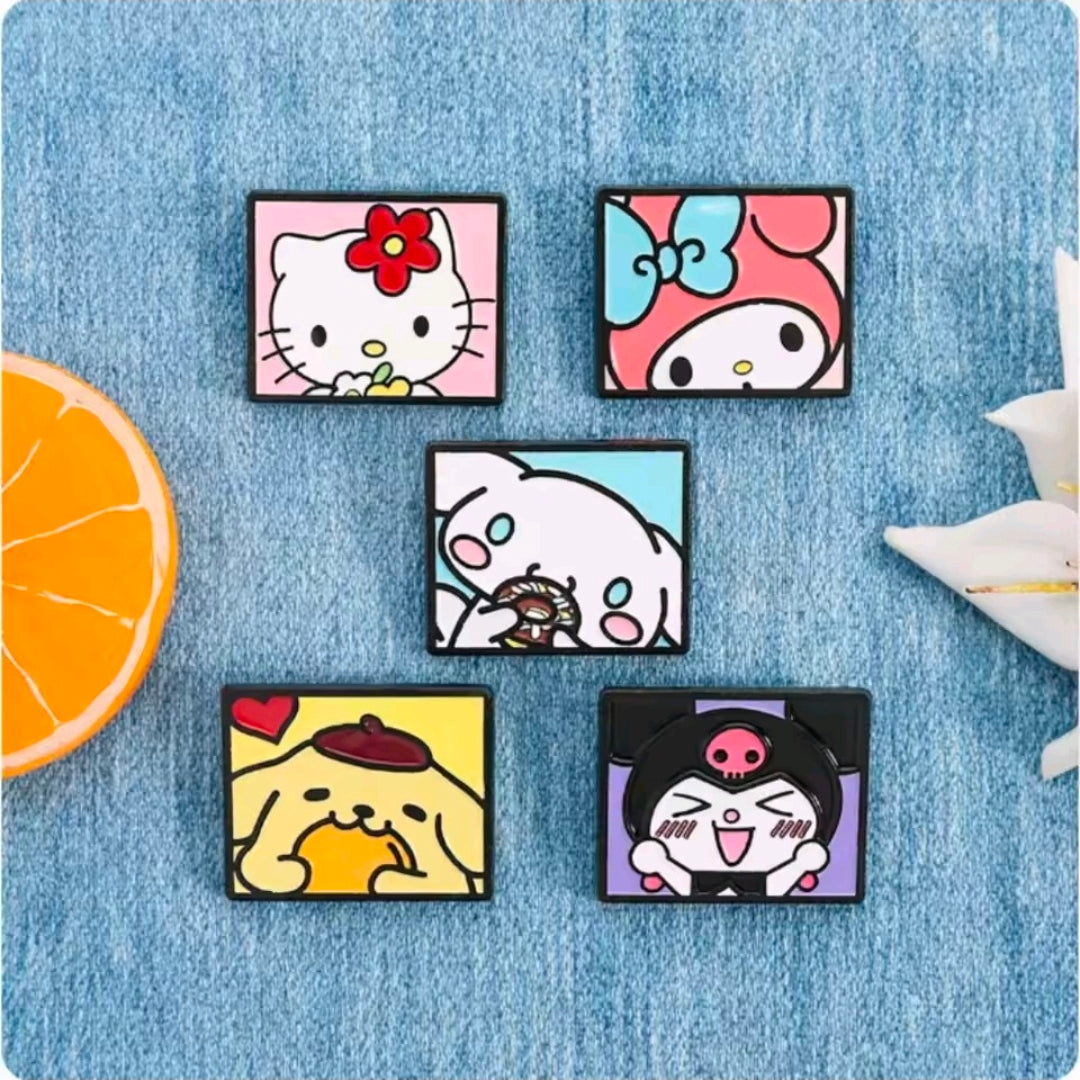 Five Sanrio enamel pins with character faces, laid out on blue fabric