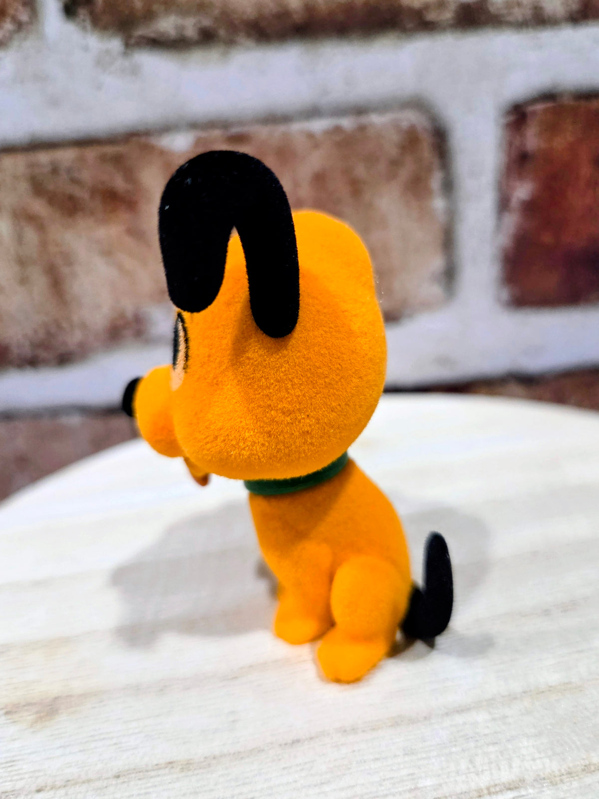 Flocked Pluto mini figure side view, orange plush with black ears and green collar