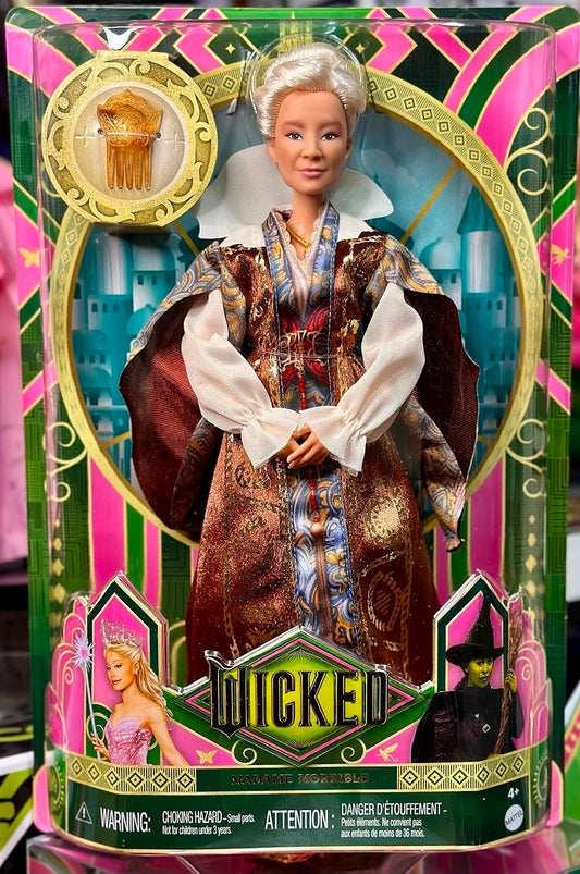 Fashion doll standing in maroon, gold, and blue patterned coat with white gloves and tiara.