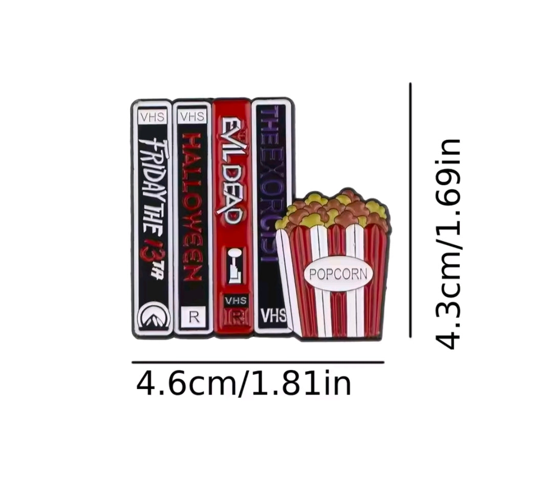 Enamel pin featuring stacked VHS tapes and popcorn graphic, red and white stripes.