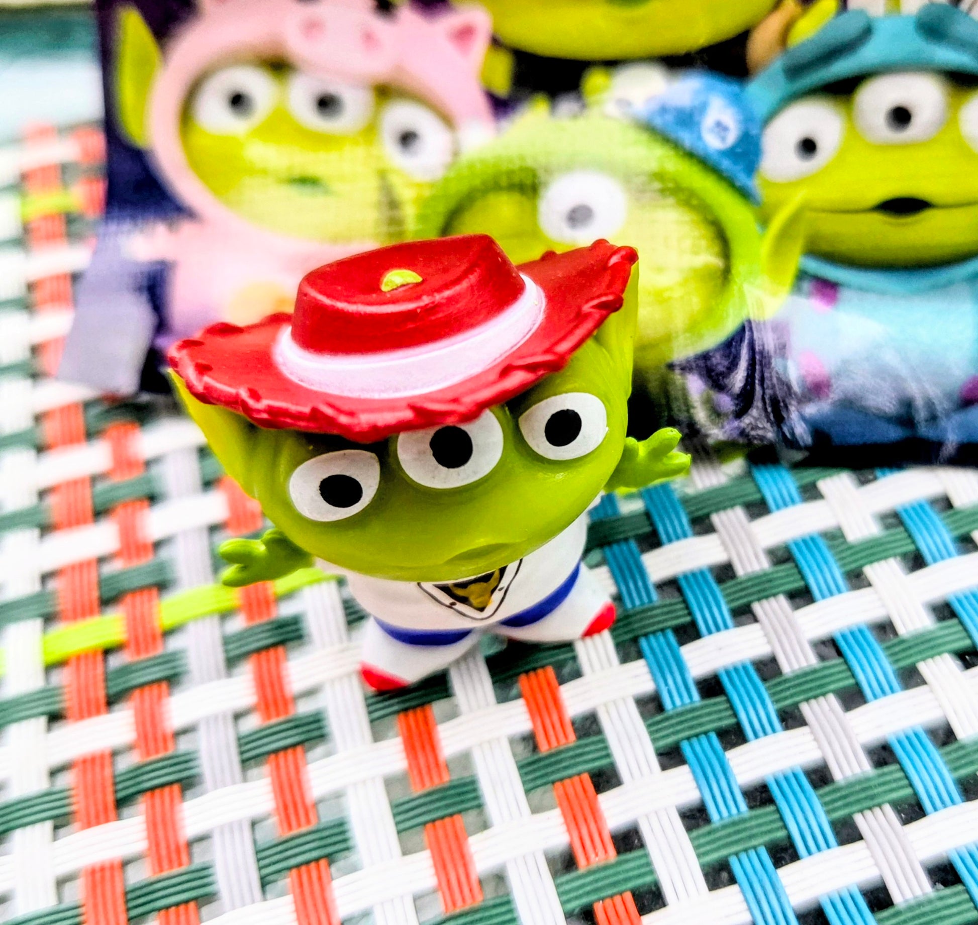 Green alien mini figure with red pizza-slice hat and white shirt, posed slightly sideways