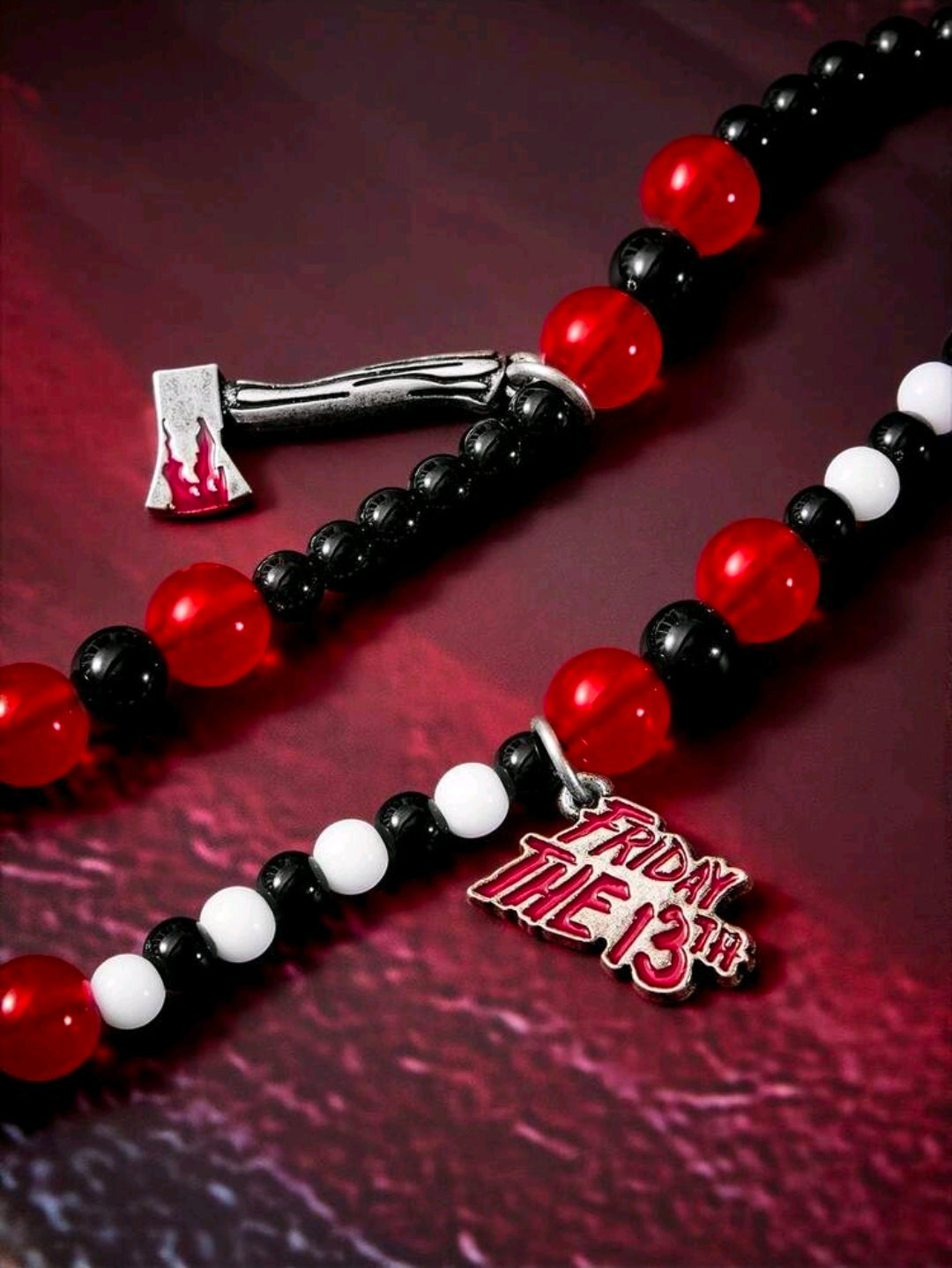 Beaded lanyard strands with red, black, and white beads and Friday the 13th tag