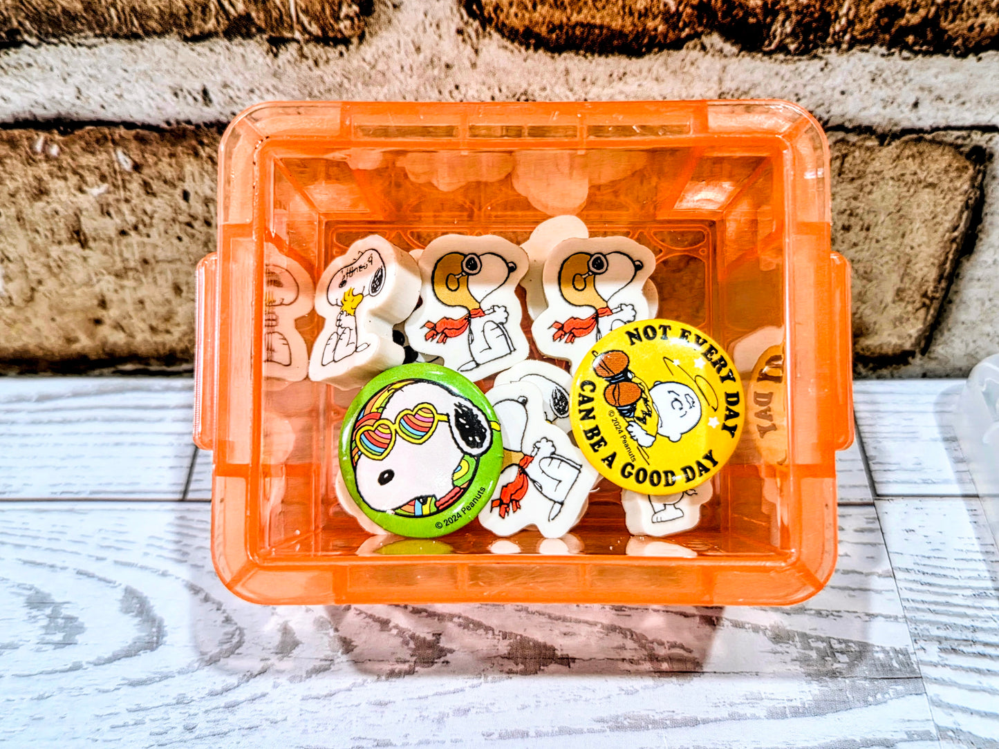 Orange organizer box with Snoopy erasers and round Snoopy-themed graphic