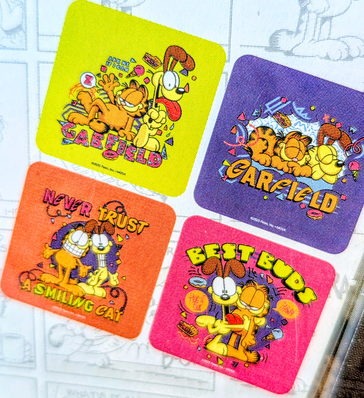 Assorted Garfield socks with four bright graphic designs: Safe Field, Never Trust, Smile, Best Buds.