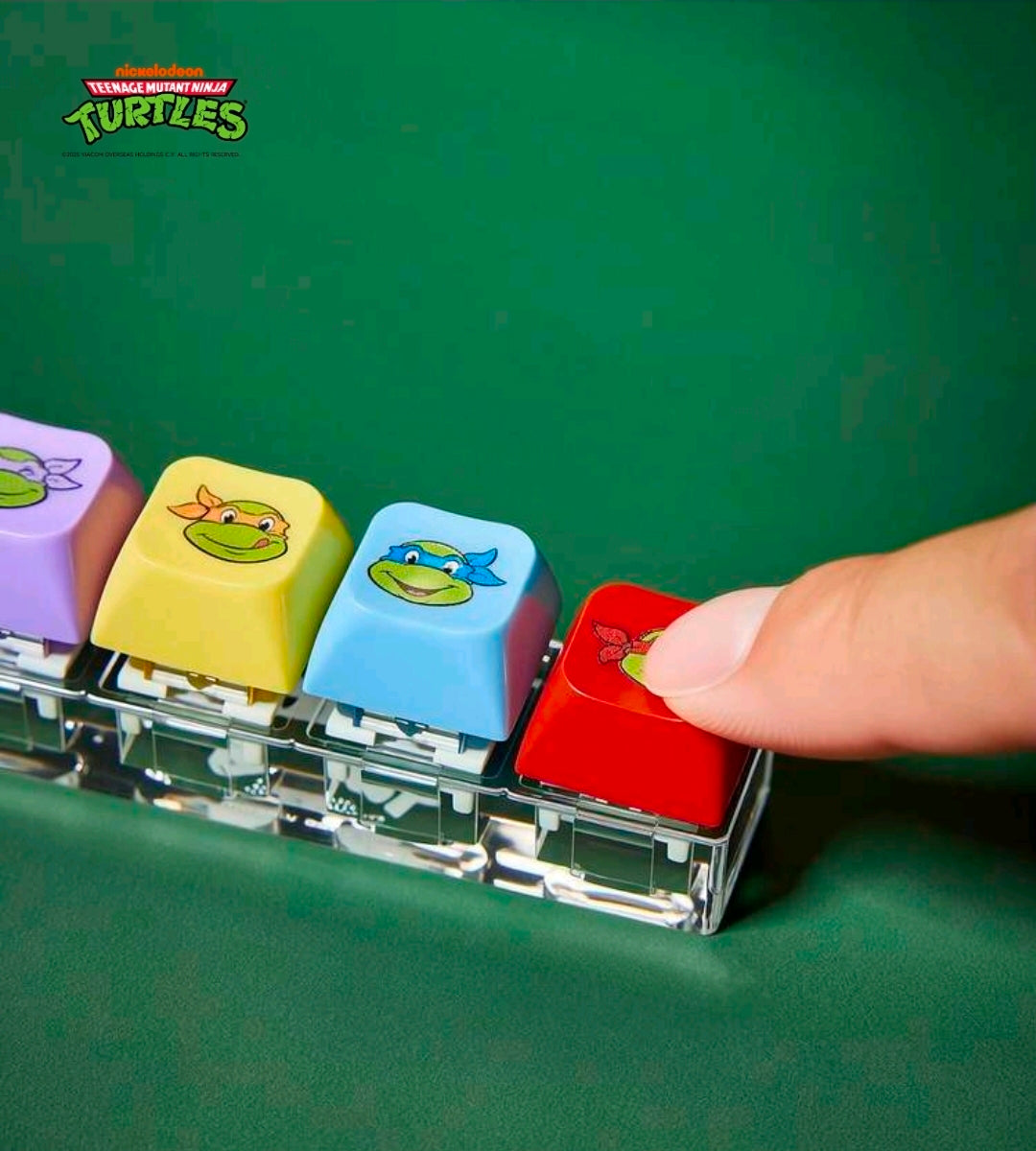 TMNT keyboard clicker keychain held by a fingertip, showing red turtle keycap