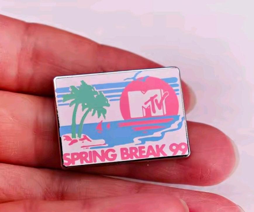 Spring Break 99 rectangular enamel pin held in hand with blue artwork and pink MTV circle