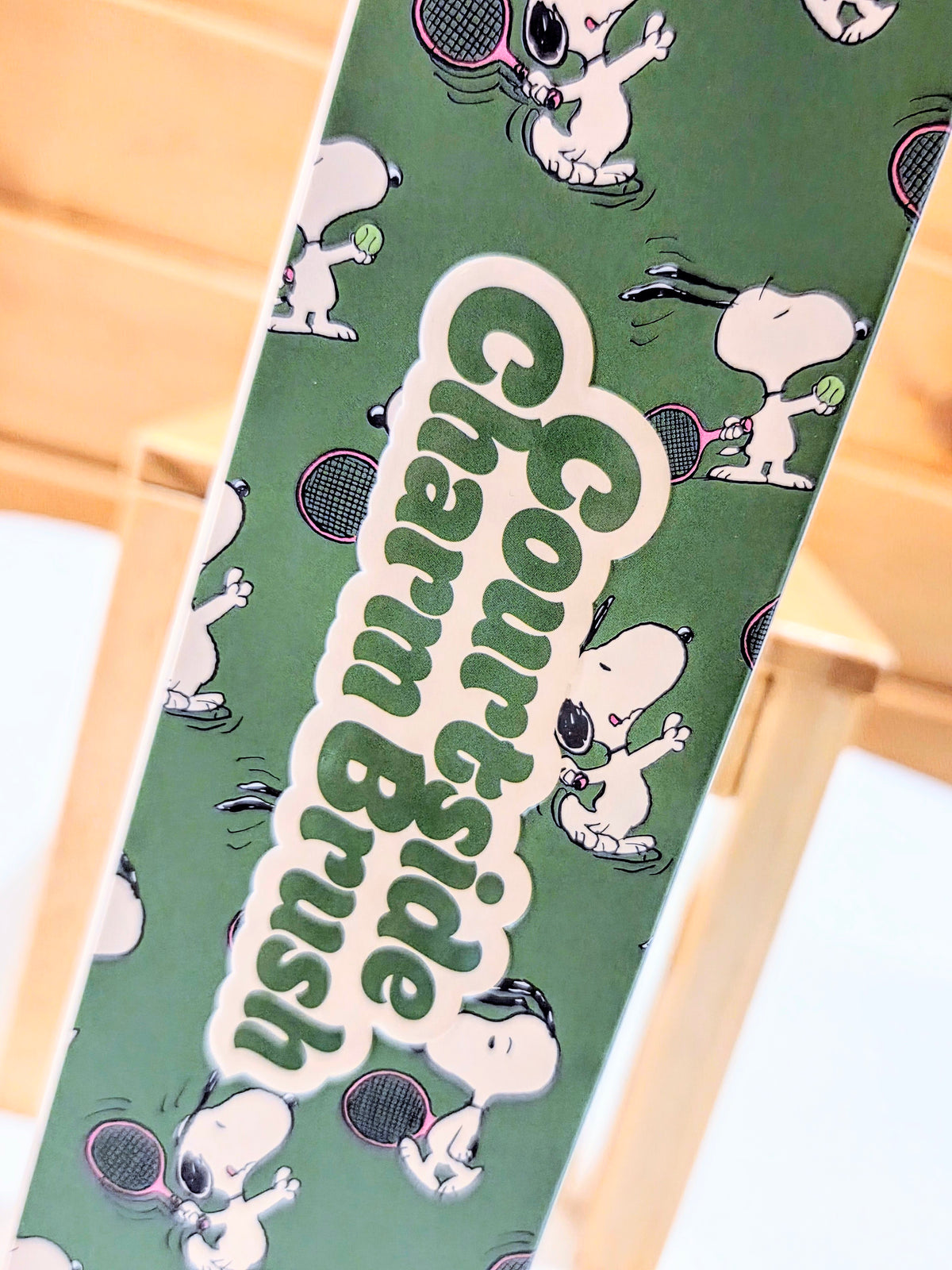 Green Peanuts tennis-themed box insert panel with Snoopy and ball icons