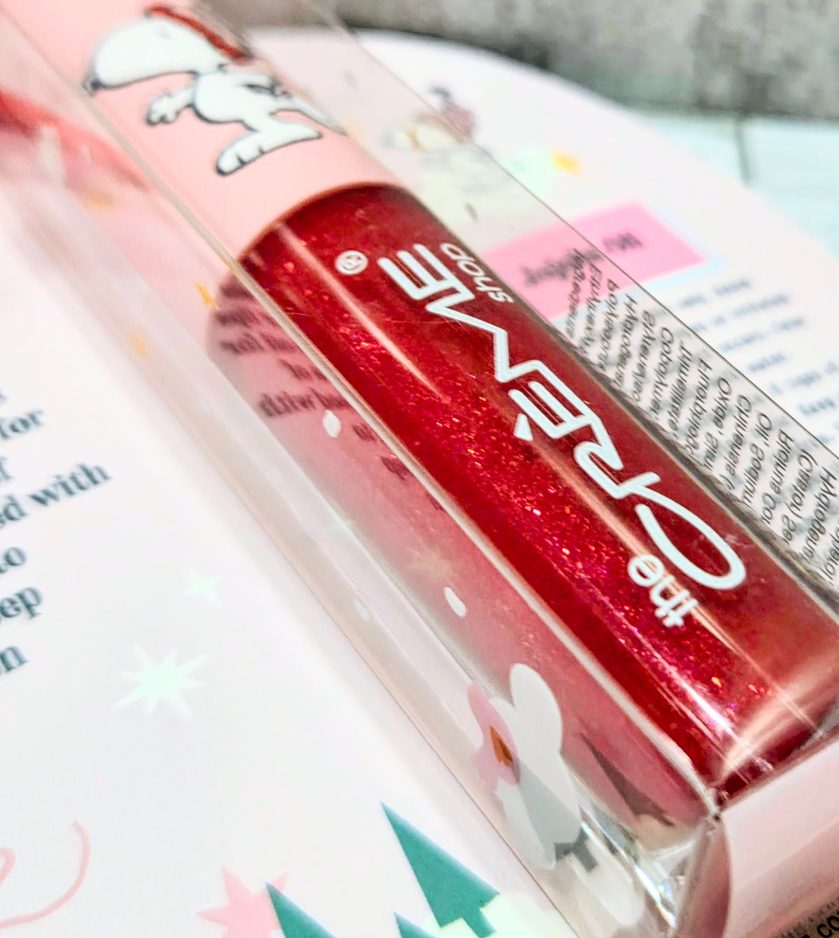 Red glitter tinted jelly lip oil tube close-up in clear plastic packaging
