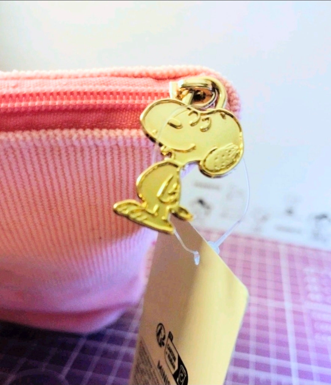 Pink corduroy pencil case with gold Snoopy keychain charm attached.