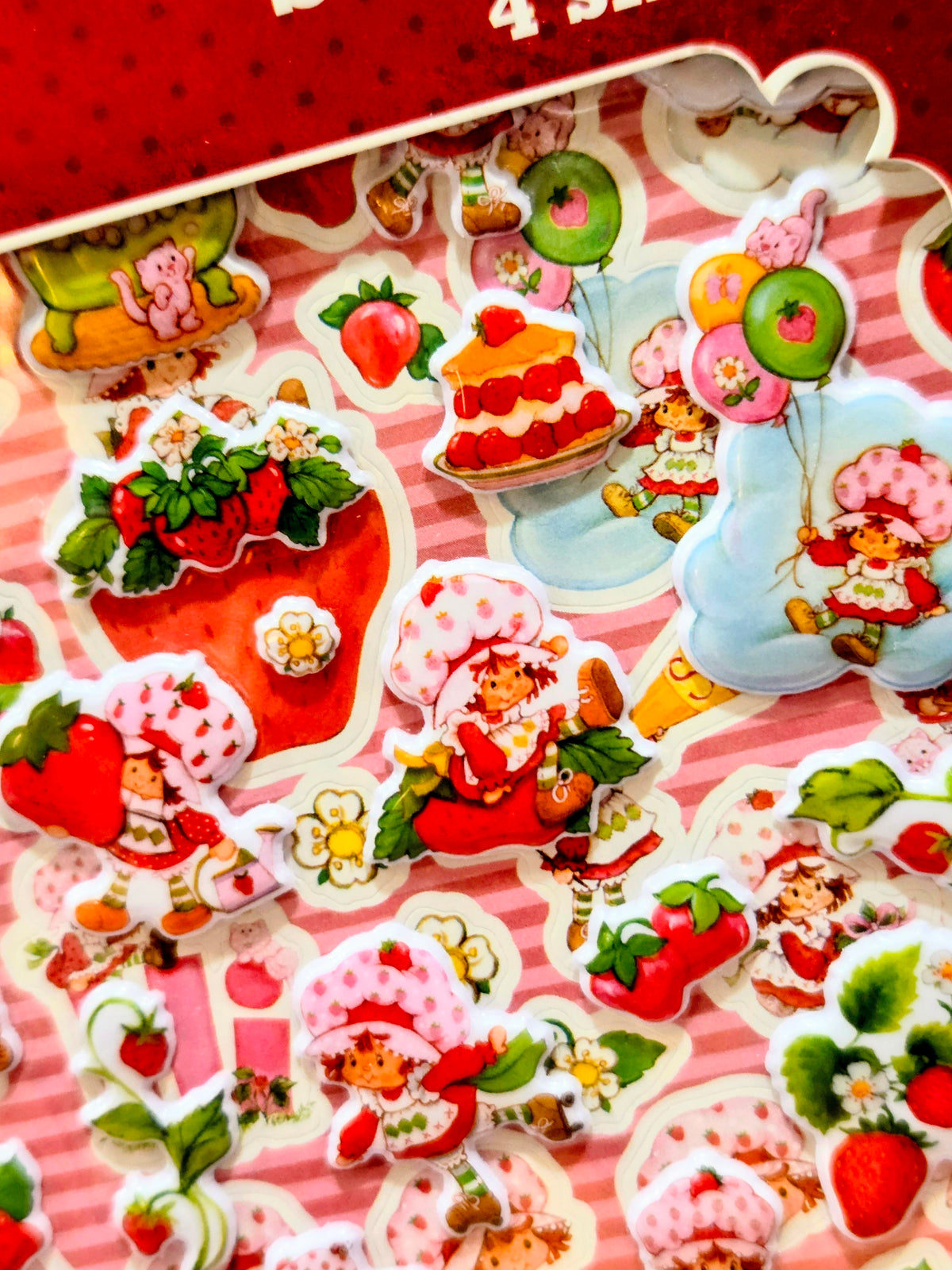 Colorful strawberry and dessert themed stickers scattered on a pink striped card