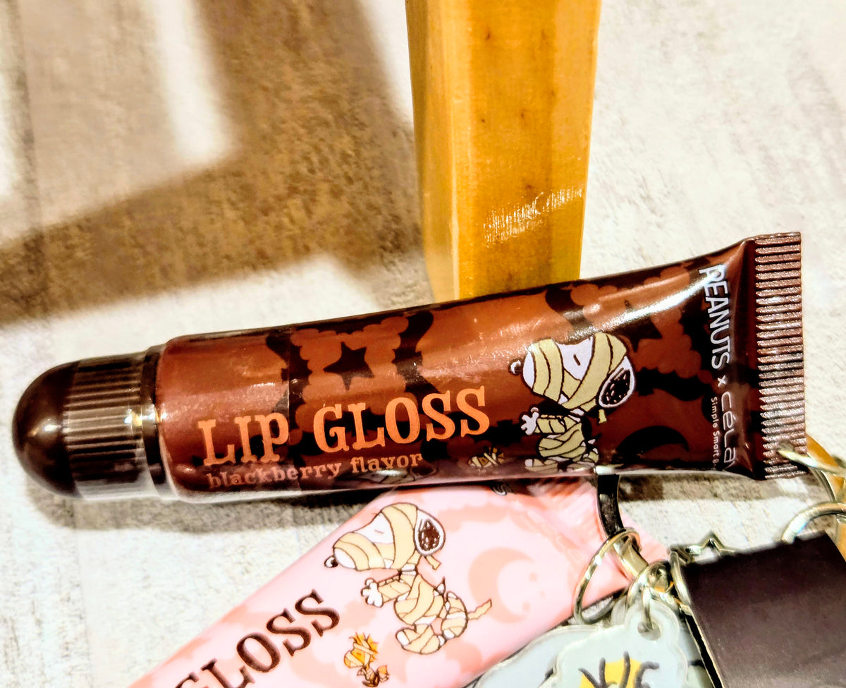 Brown lip gloss tube and pink lip gloss tube with Halloween Peanuts design