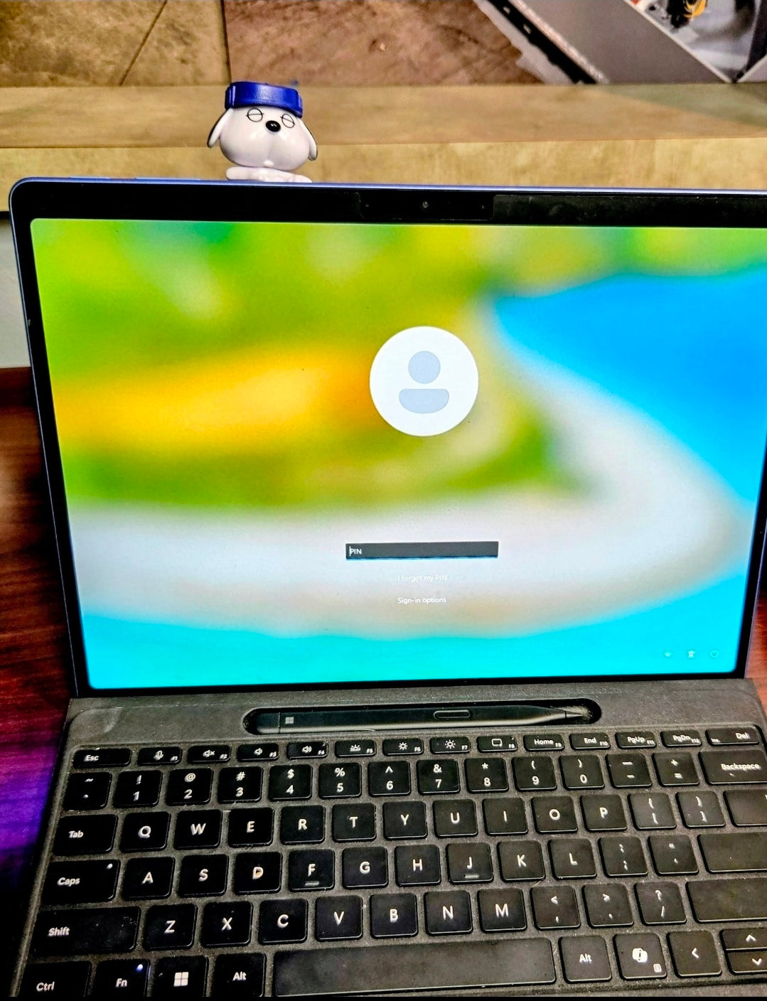 Blue-capped Olaf mini clip-on sleeping figure standing on laptop keyboard