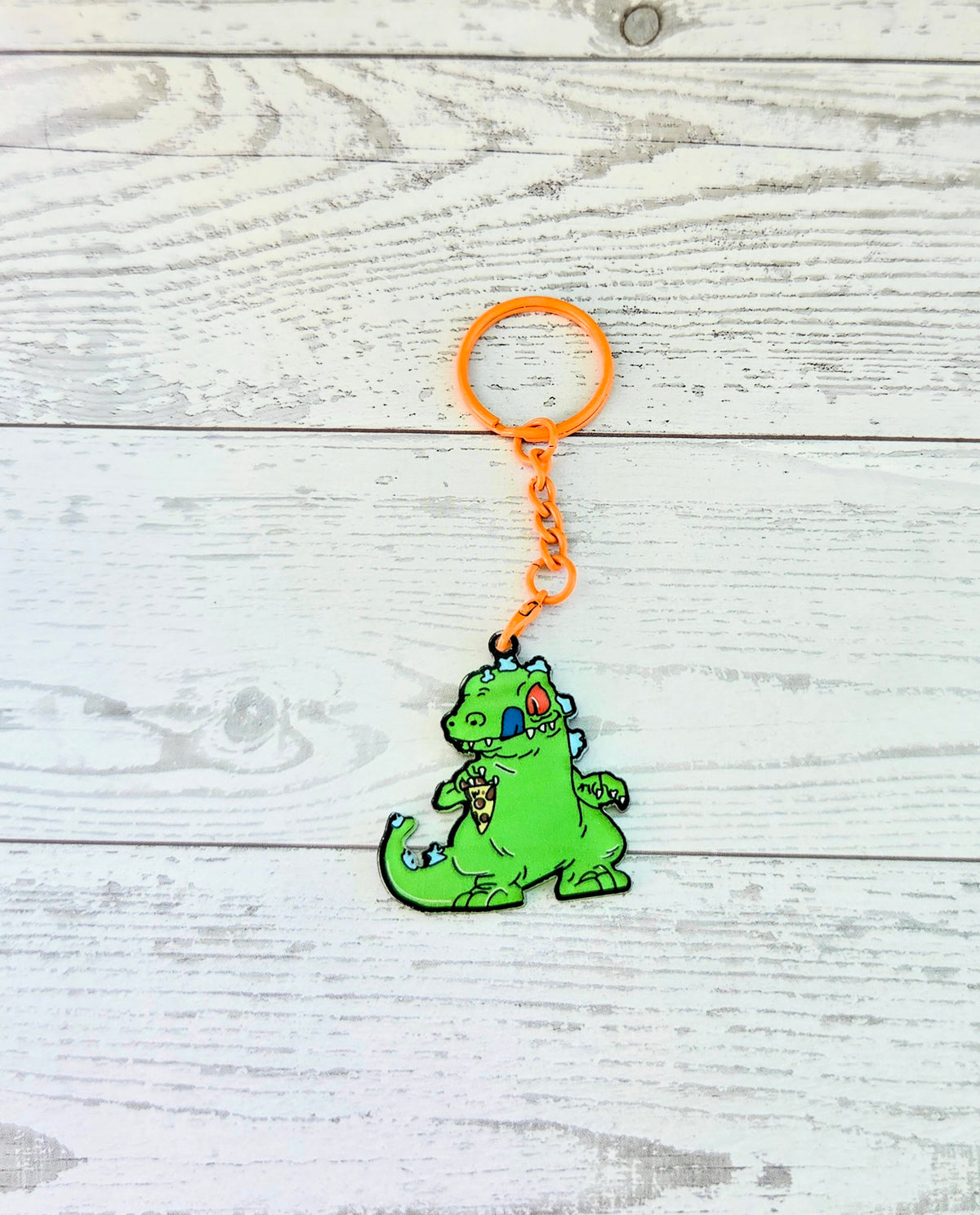 Orange-ring acrylic keychain with a small green Reptar crouching on orange chain
