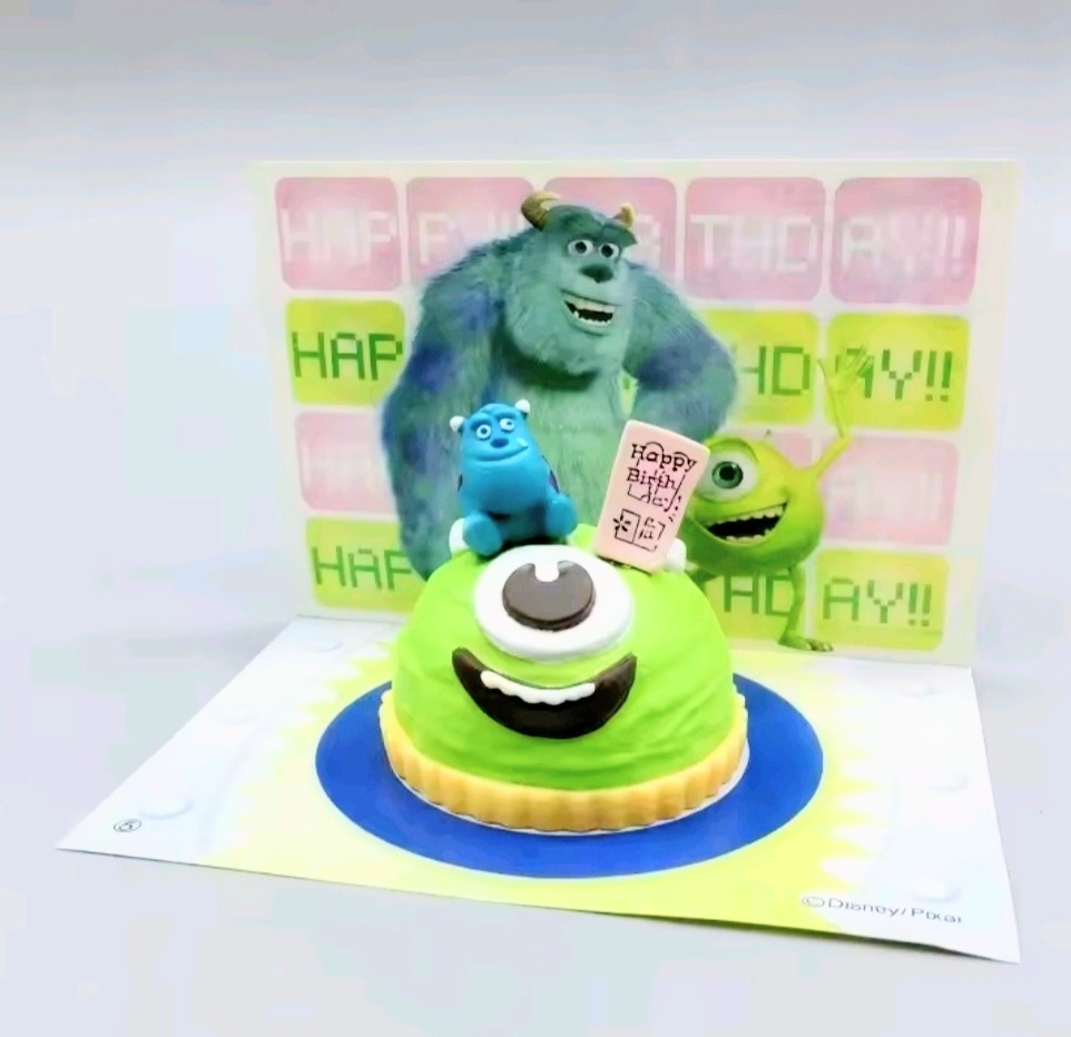 Green sponge cake mini figure with teal monster and Happy Birthday card on display stand