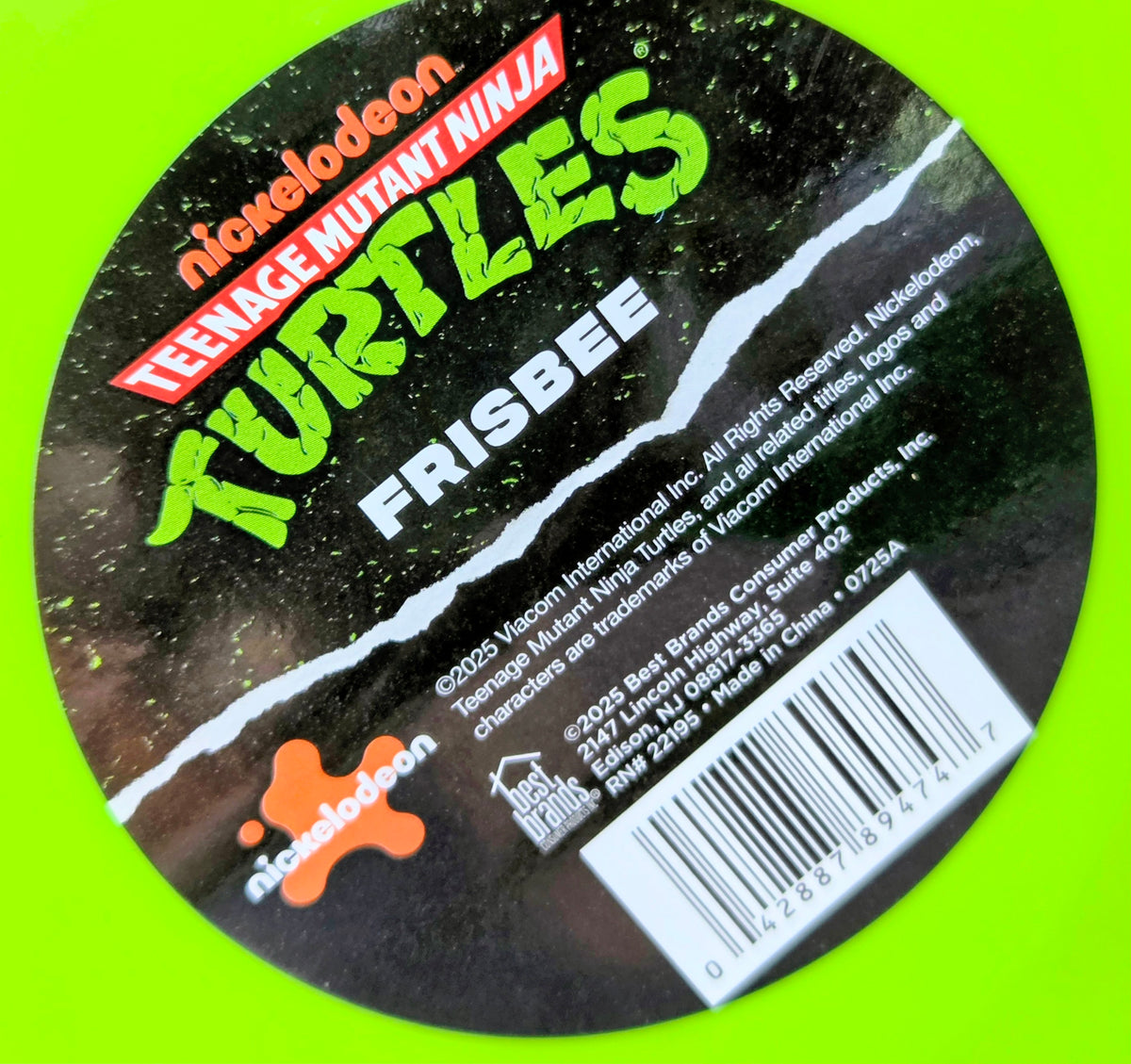 Neon green frisbee with black back label, TMNT text, and barcode sticker