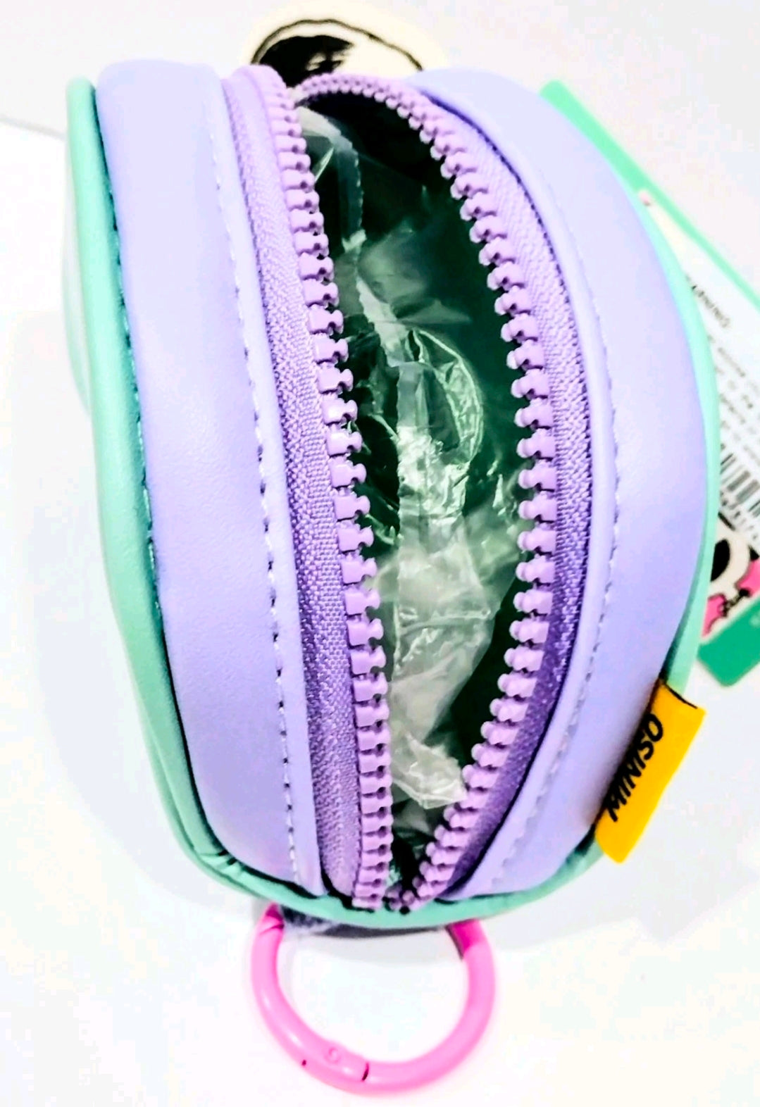 Mint mini zip coin purse open with green lining and purple zipper trim