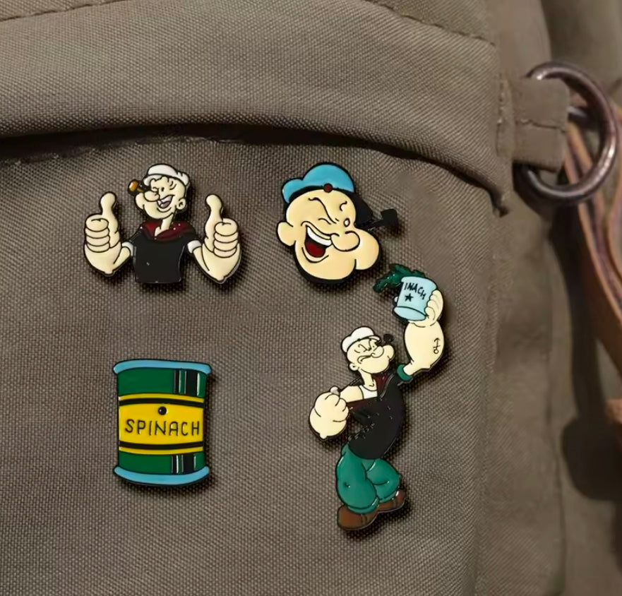 Four-piece Popeye enamel lapel pin set on fabric: sailor face, Popeye, spinach can
