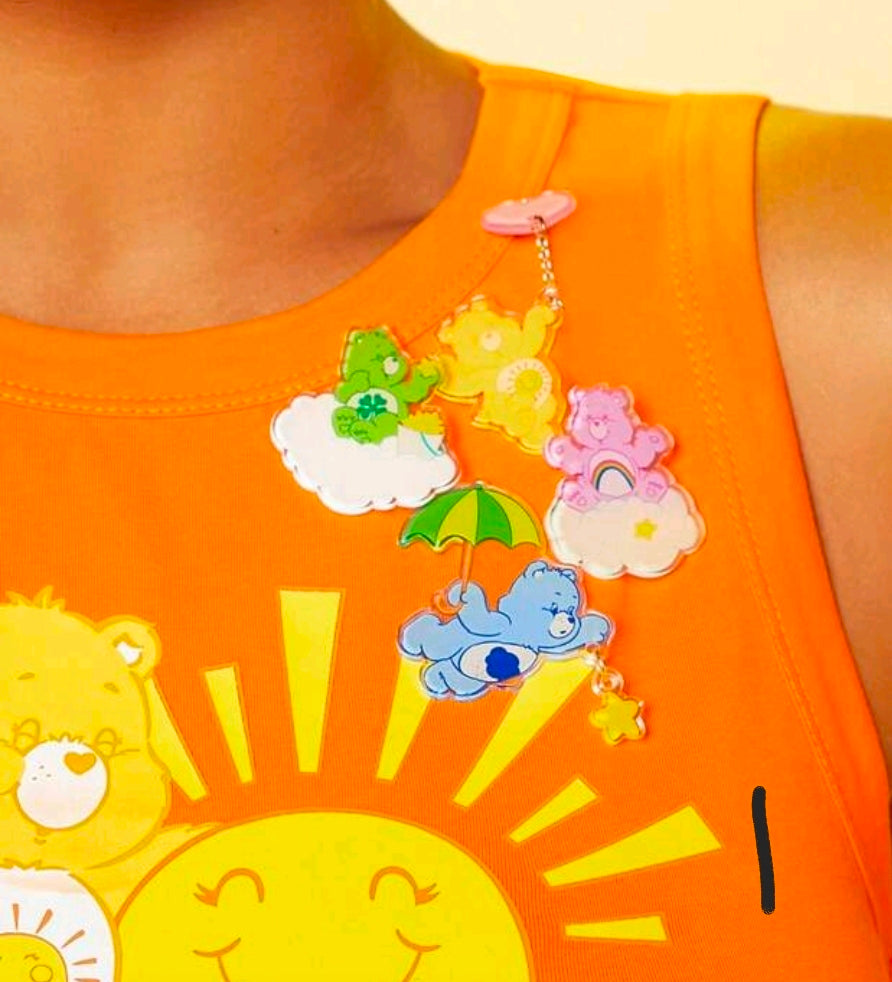 Acrylic bear brooch pin on orange shirt with cloud-and-star charm dangles