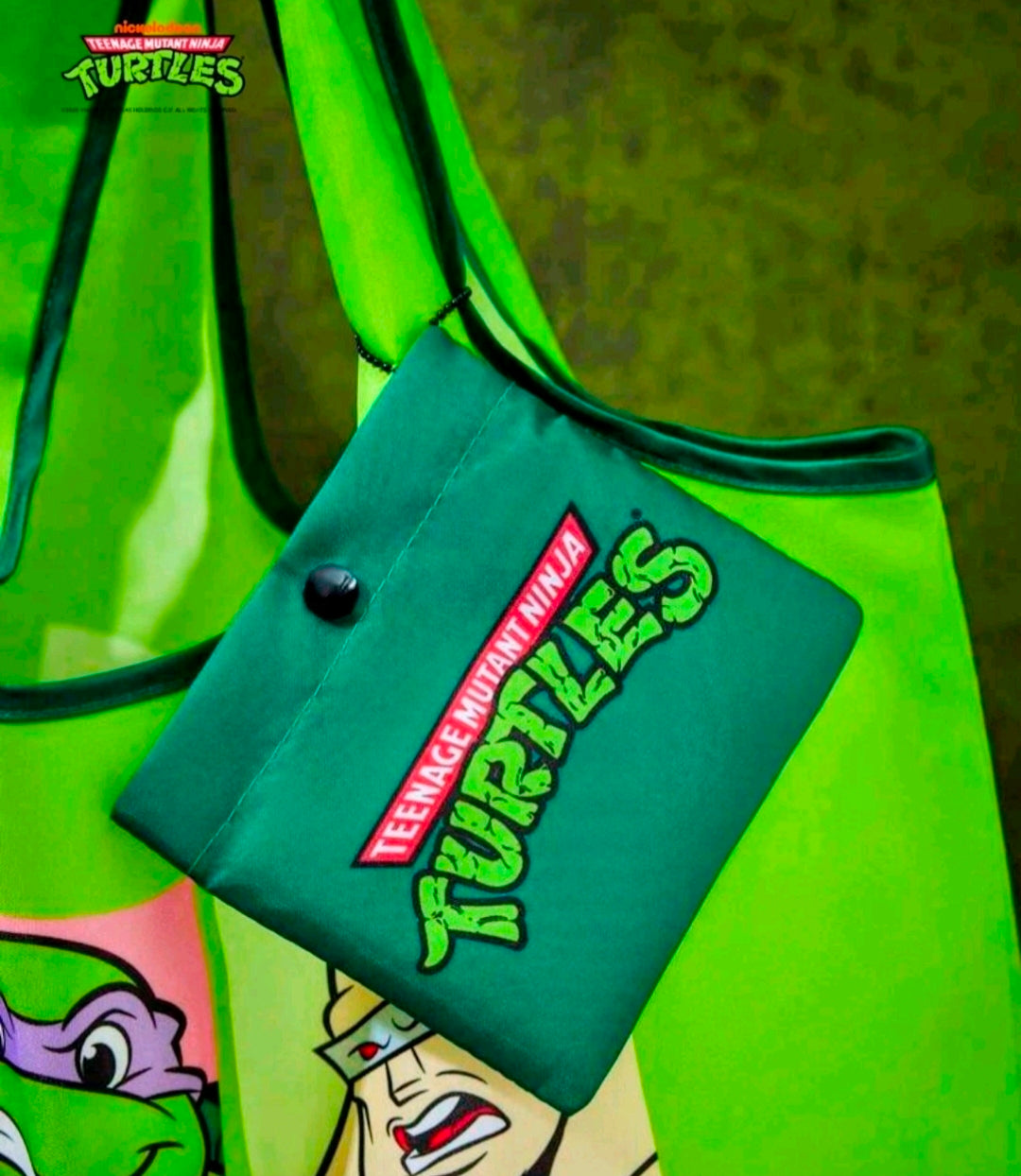 Green tote bag with colorful cartoon character graphic panel and logo keychain tag