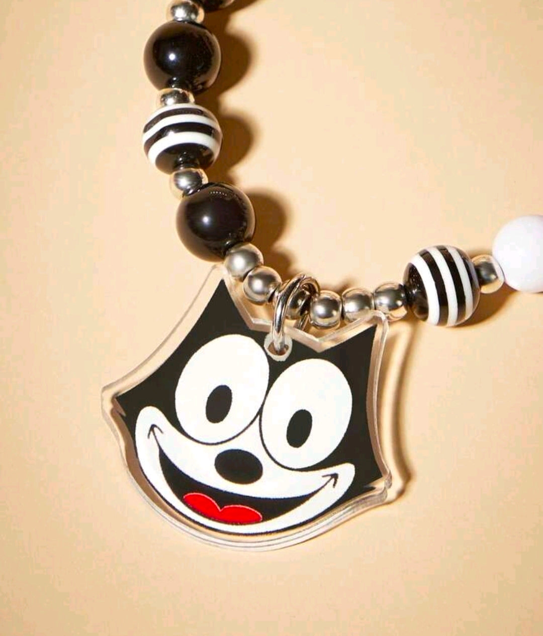 Black and white beaded charm lanyard featuring Felix face charm and striped bead spacer