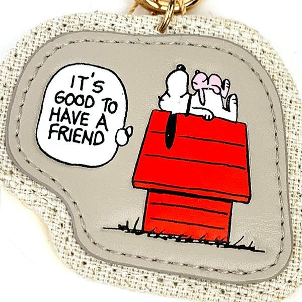 Close-up of fabric keychain fob with red doghouse scene and outlined speech bubble patch