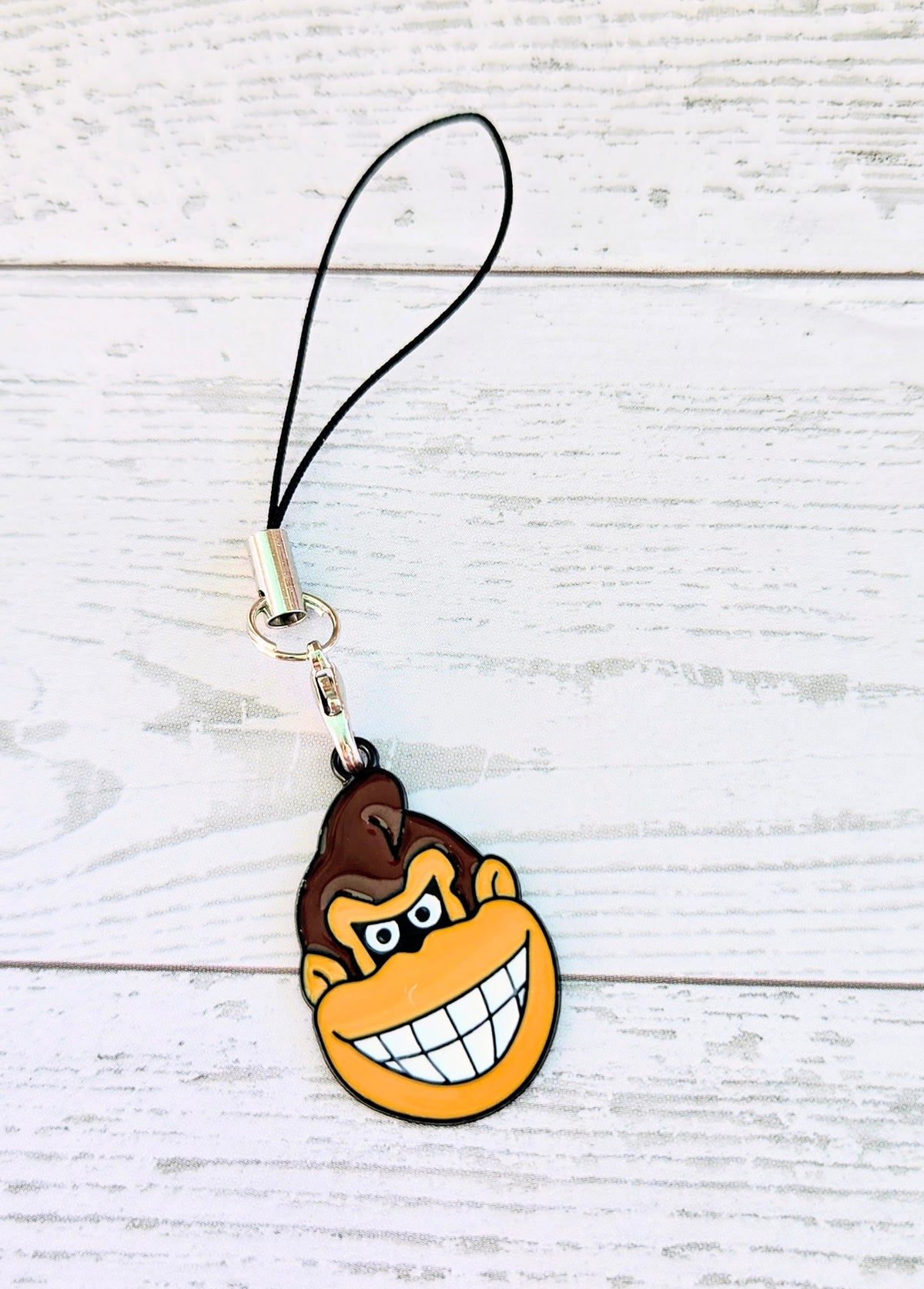 Black cord phone charm wrist strap with Donkey Kong grin enamel face charm