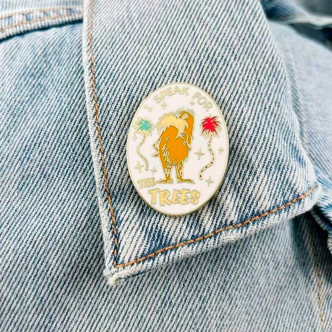 Oval Speak for the Trees enamel pin with lion illustration on denim jacket.