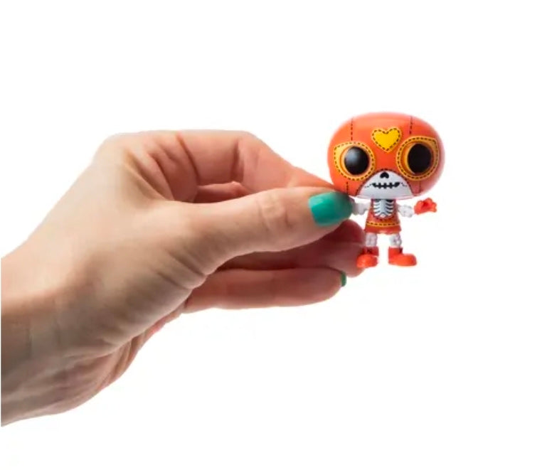 Orange Halloween vinyl mini figure held in hand with heart-face skull and crown