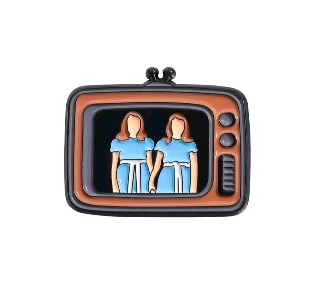 Enamel TV screen pin with two blue-shirt figures on an orange TV background.